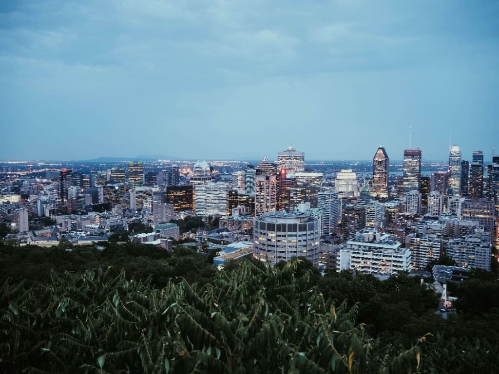Montreal skyline at dusk seen from Mount Royal over the treetops