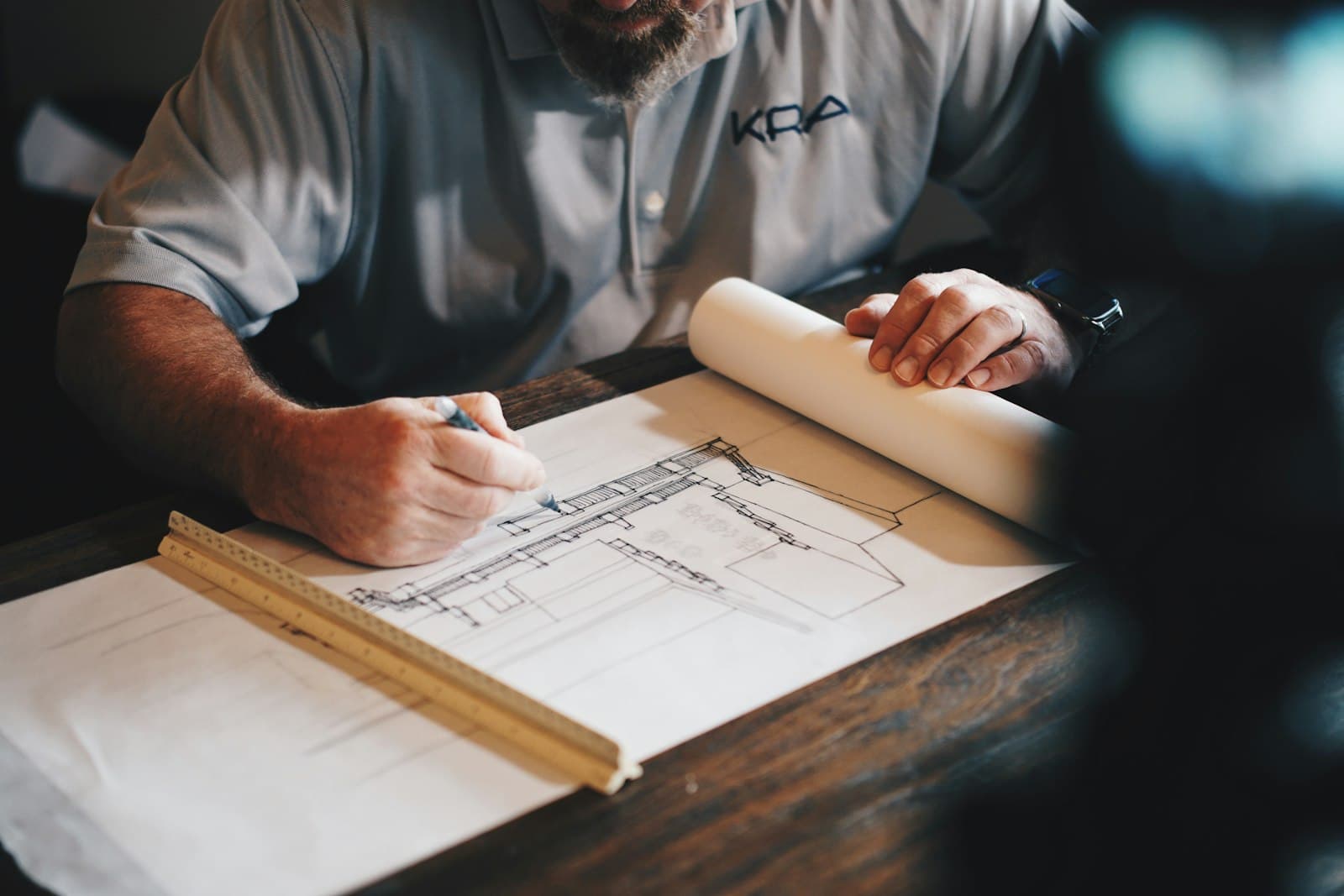 An architect marking a technical drawing of a building on a desk