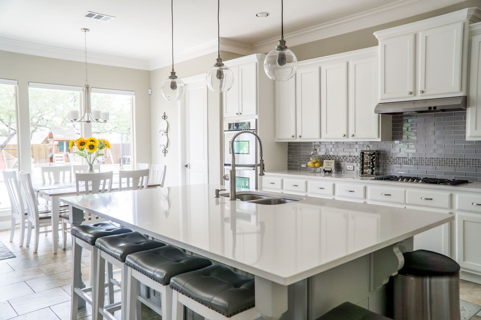 A staged condo kitchen with island stools, stainless appliances, and a dining table