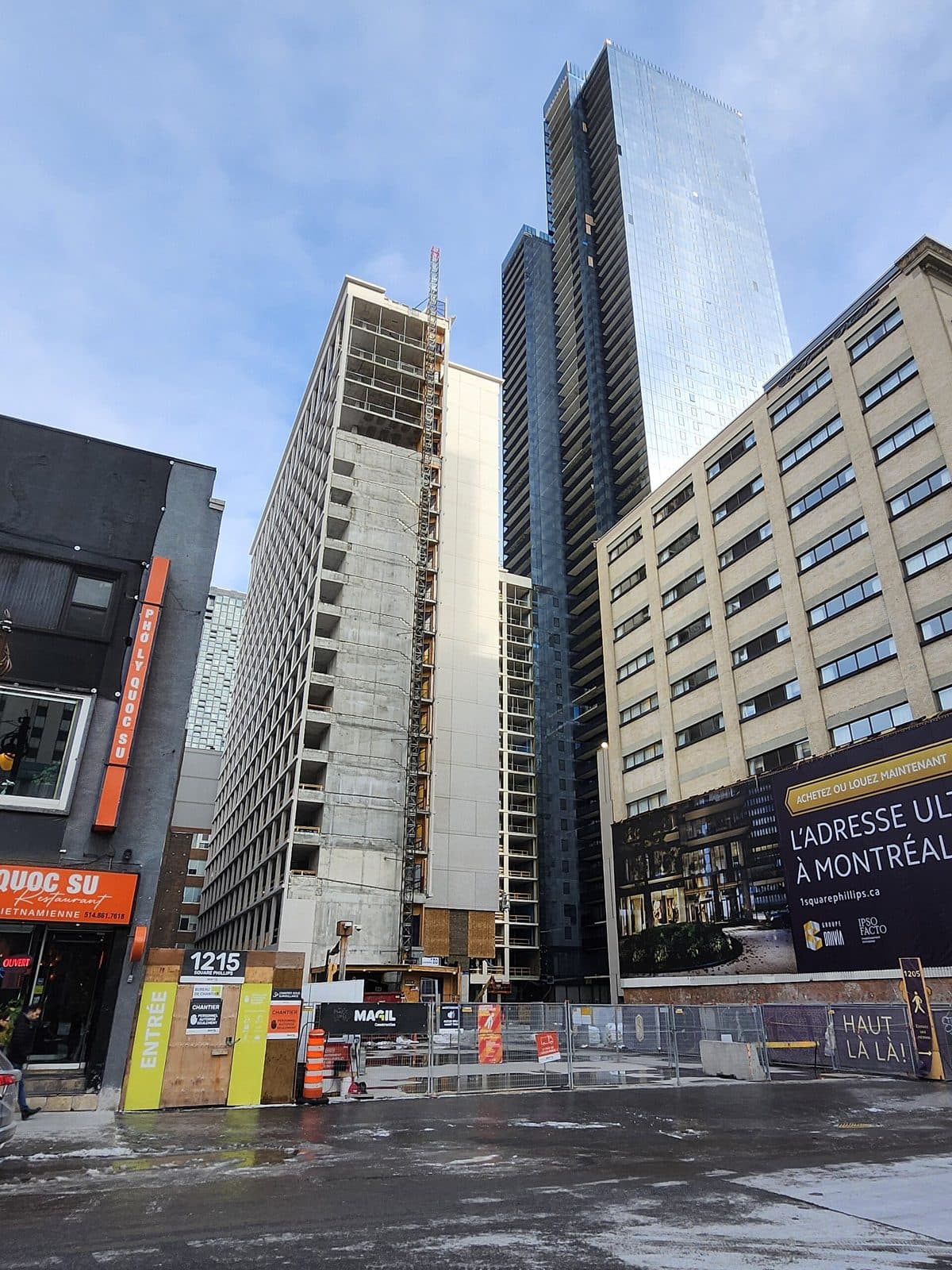 The dark glass tower of 1 Square Phillips behind construction hoarding