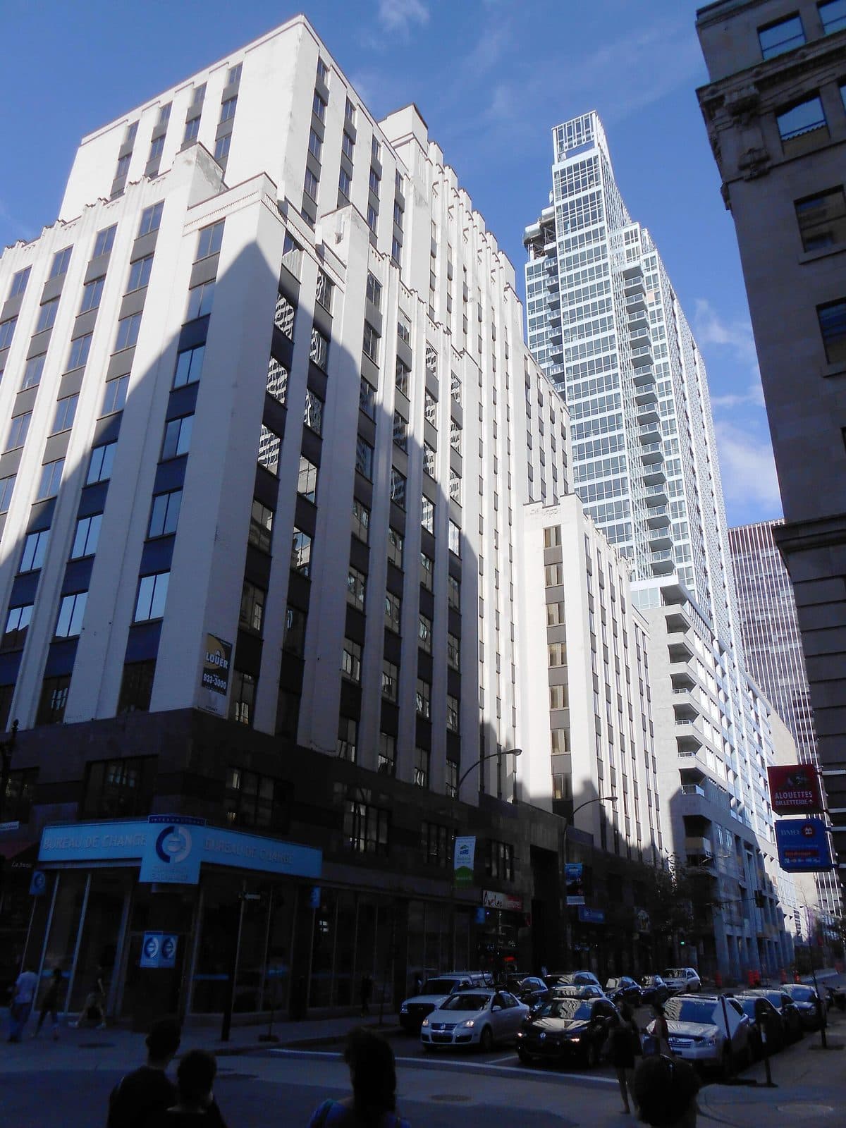A white 1929 office building in front of the glass Altitude tower