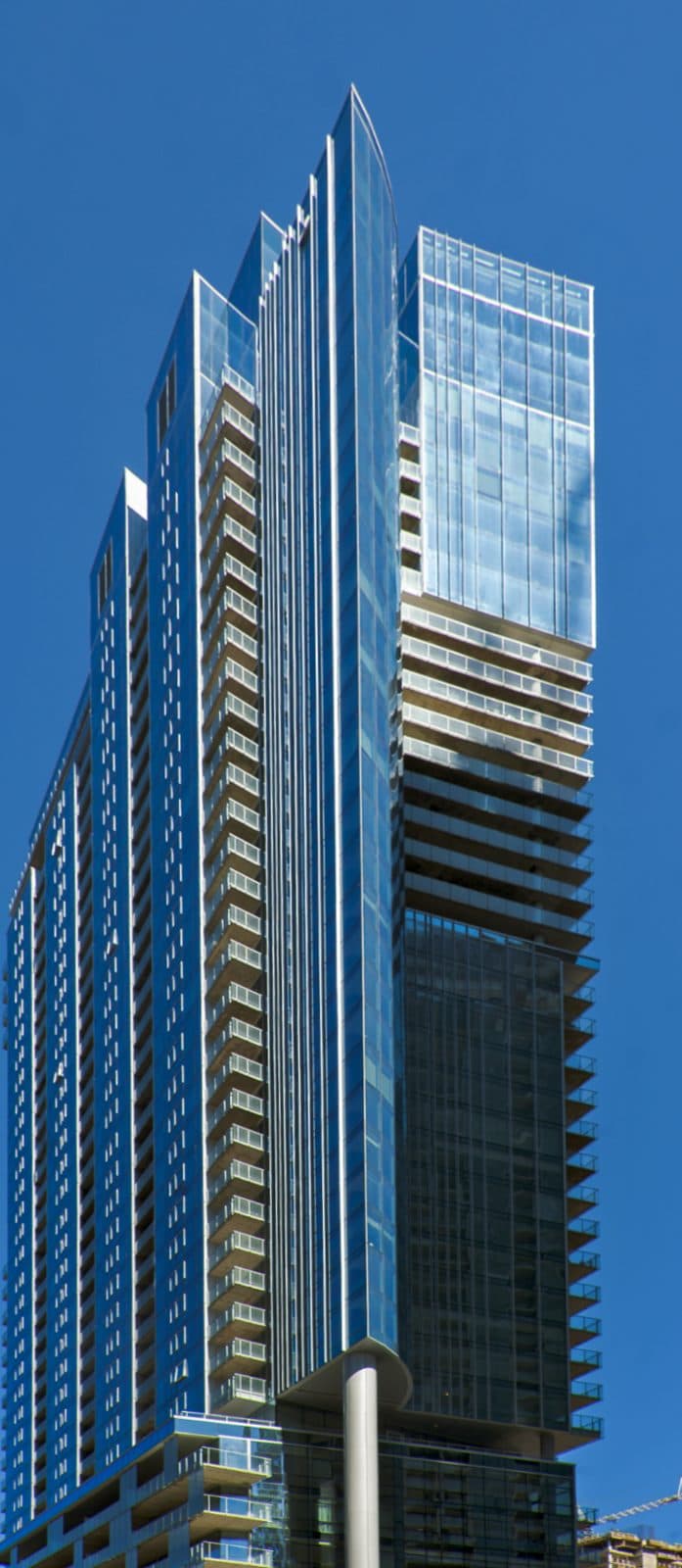 Icône's slim blue-glass west tower against a clear sky