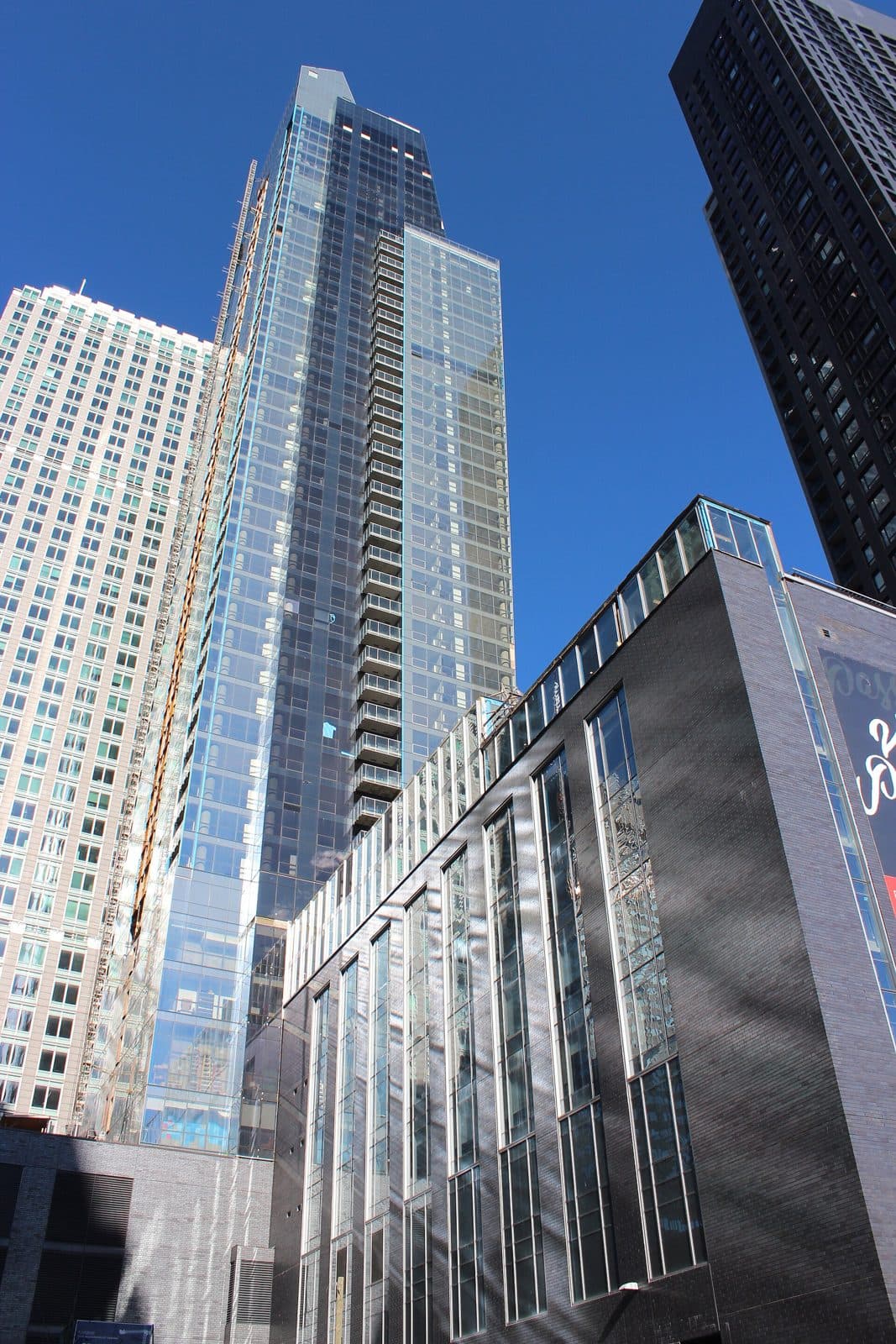 L'Avenue's tall glass tower rising behind a dark podium