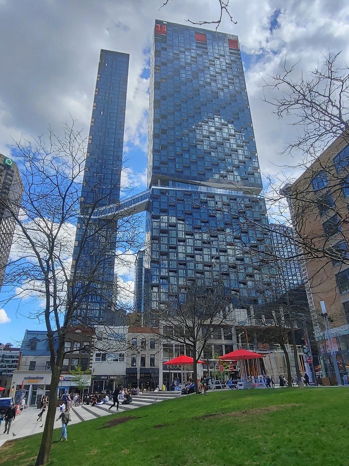 Maestria's two glass towers joined by a skybridge, seen from a park