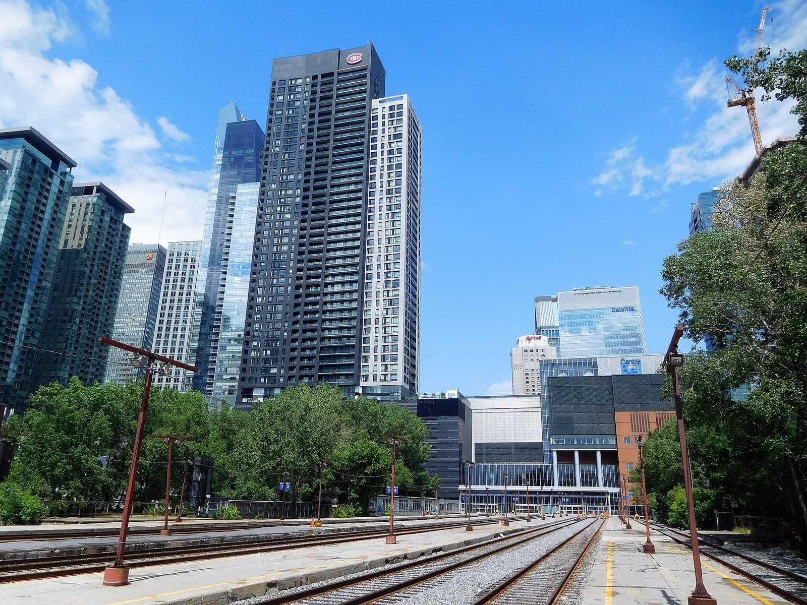 The Tour des Canadiens towers rising beyond rail tracks and trees