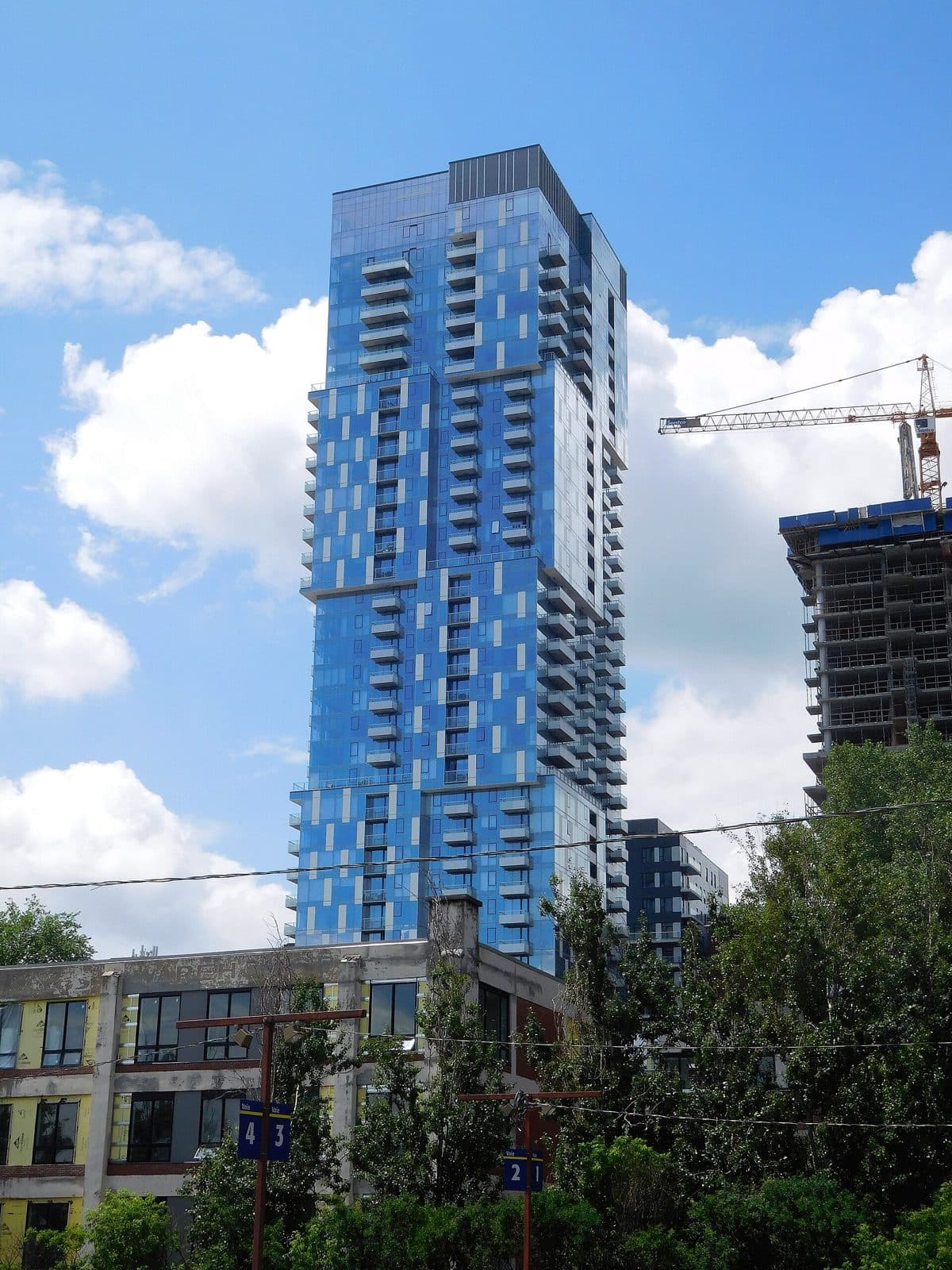 A blue glass YUL tower above older low buildings, with a crane nearby