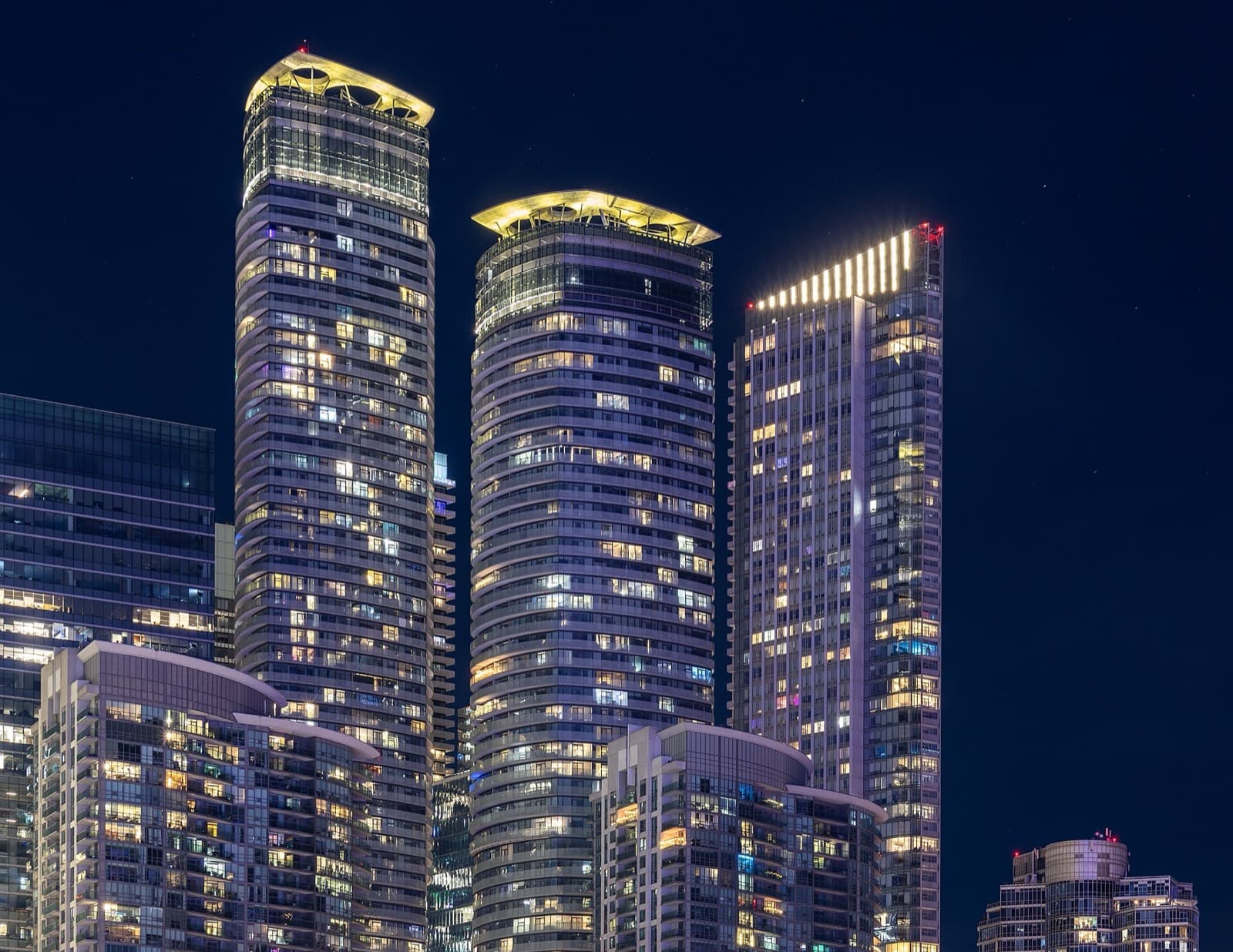 The two ICE Condominiums glass towers lit up at night on York Street in Toronto