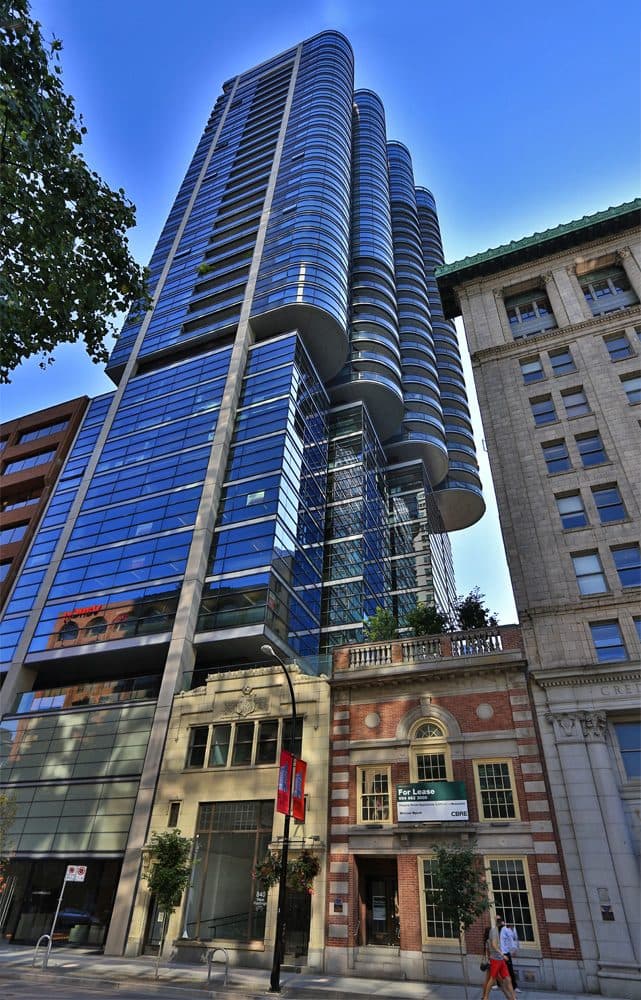 Jameson House's curved glass tower above heritage storefronts on West Hastings Street