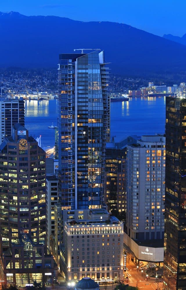 The Private Residences at Hotel Georgia lit up at dusk with the harbour behind