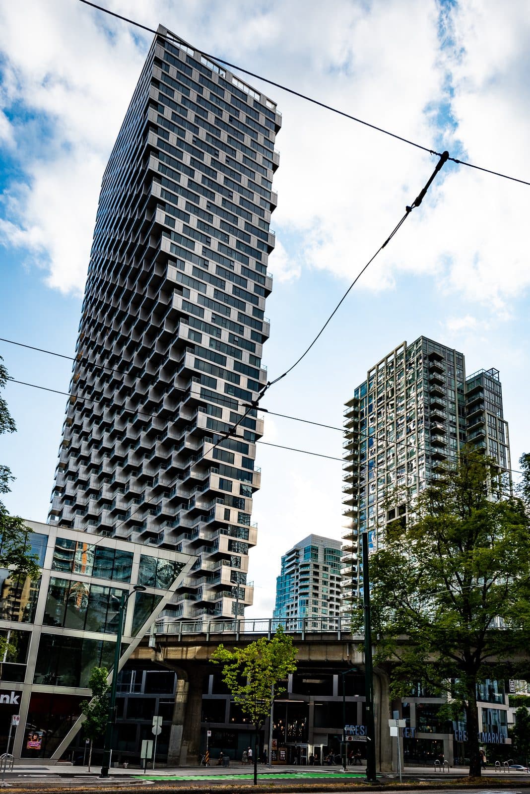 Vancouver House rising above the street, its stacked balconies widening toward the top