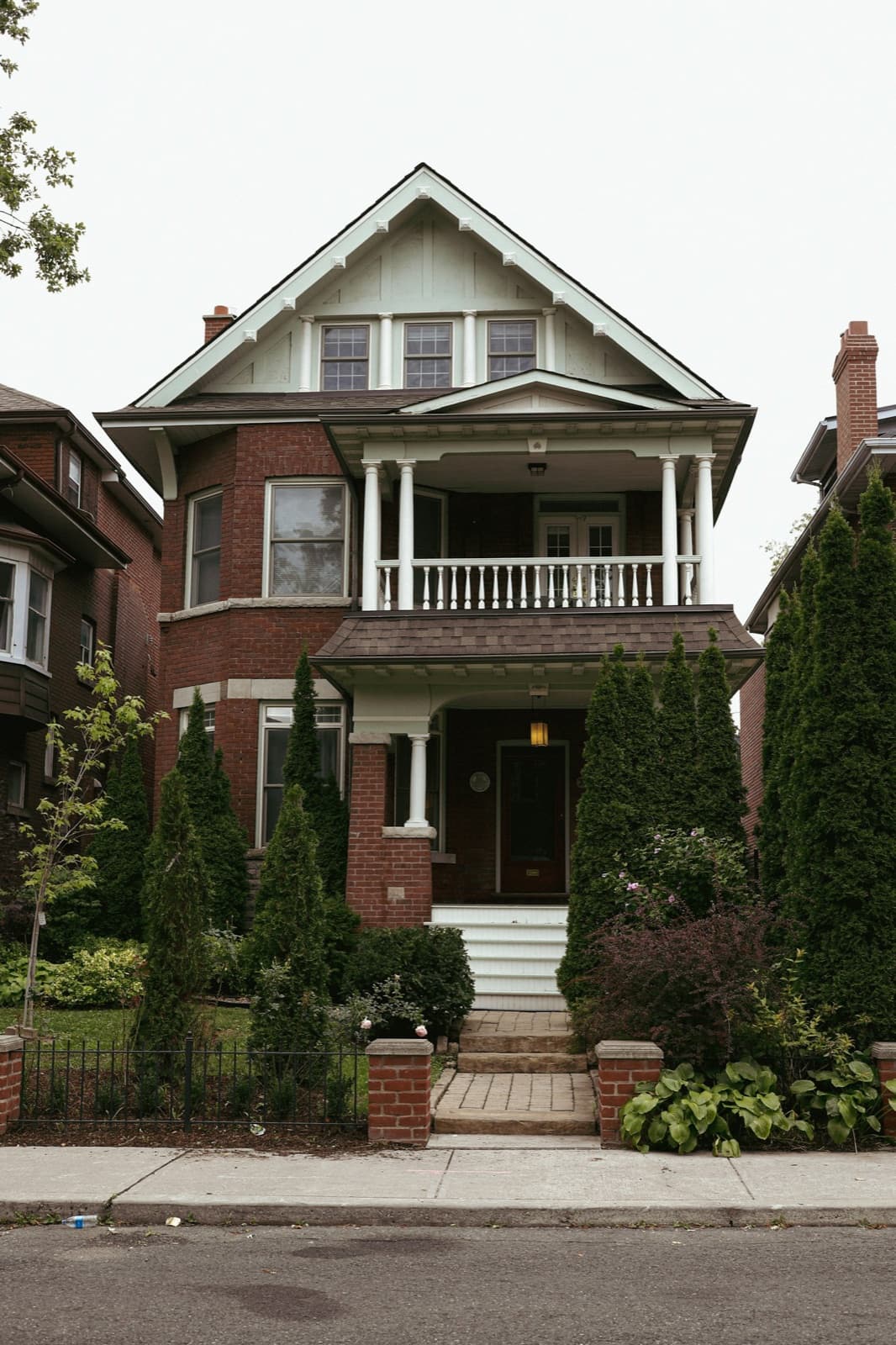 A large red-brick house with a white porch on a Toronto residential street